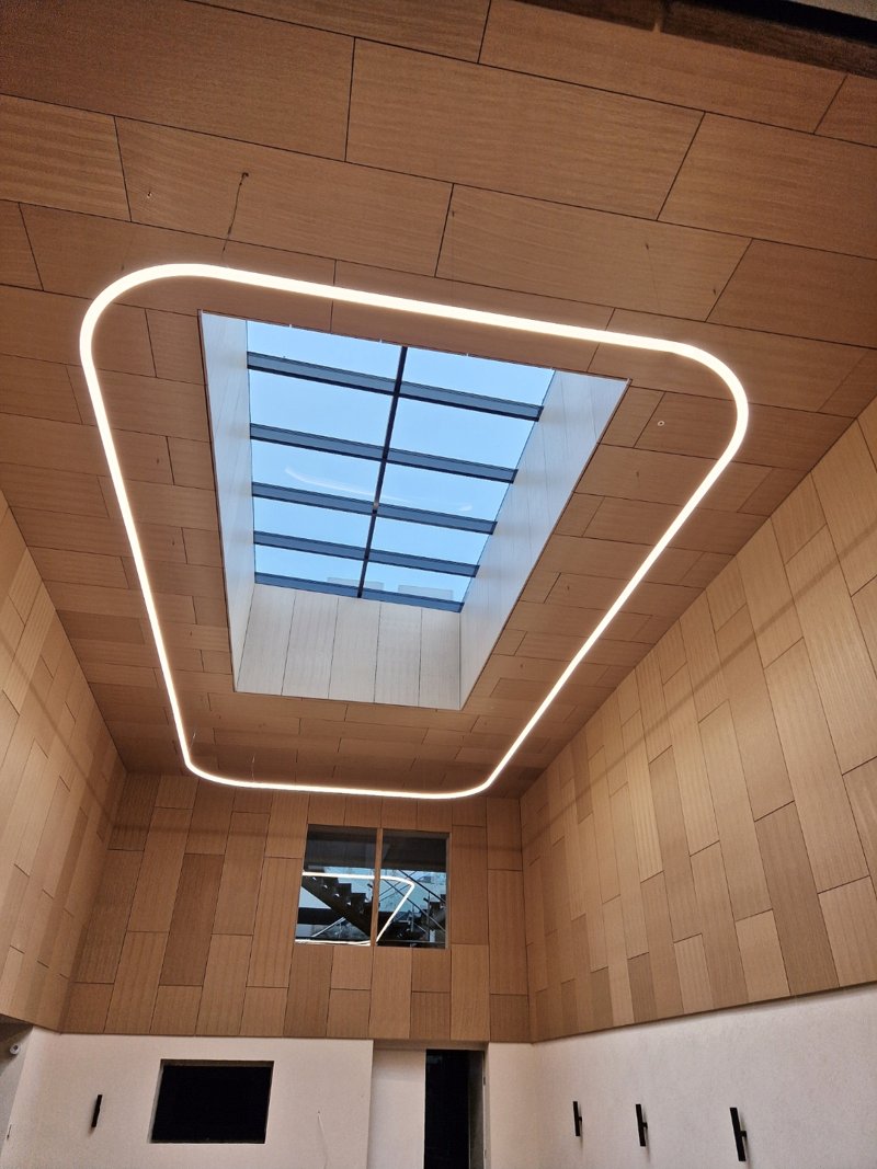 LED profile lighting ring around a skylight in a timber-clad room